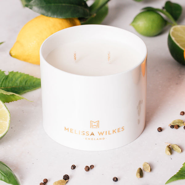 A white fine bone china two wick candle with 22-carat gold decoration of the ‘Melissa Wilkes England’ branding surrounded by fresh lemons, limes and cardamon to showcase the ingredients. This vibrant, citrus scent that we’ve named Pomelo Bitters sings with sunshine. Zesty aromas and bright herbs capture the infectious spirit and energy of the Mediterranean.
