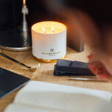 This is a photograph of Melissa at her wooden top desk with her favourite silver fountain pen creating her to do list for the week ahead in her paper diary. Lit on the desk is her citrus scented candle Pomelo Bitters . It a scent Melissa created for vibrancy and creativity. Also present are the gold wick trimmers so she defiantly prepared the candle correctly before she lit it. 